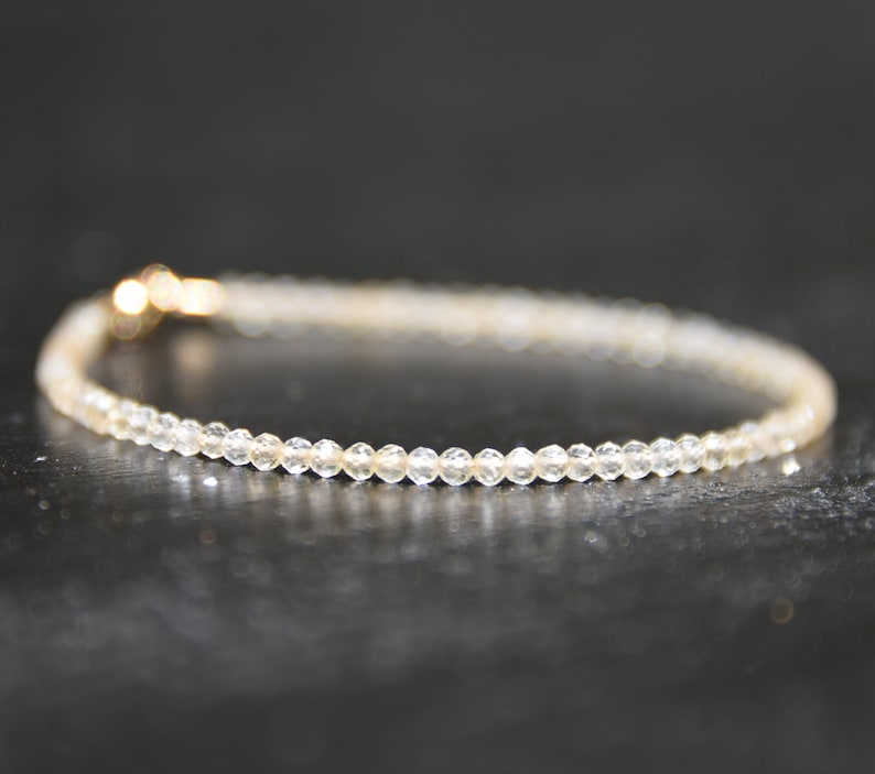 K&ouml;nnte beinhalten: Ein zartes Armband aus kleinen, klaren Perlen mit einem goldenen Verschluss.