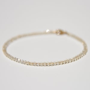 K&ouml;nnte beinhalten: Ein zartes Armband aus klaren Quarzperlen mit einem goldenen Verschluss.