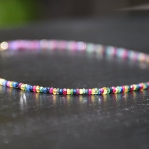 Pu&ograve; includere: Una delicata collana composta da piccole pietre preziose colorate. La collana presenta uno spettro di colori, tra cui rosso, blu, verde e giallo, creando un accessorio vivace. La collana &egrave; lunga circa 40 cm.