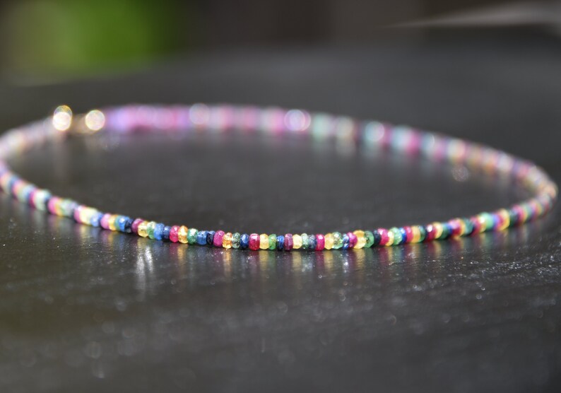 Pu&ograve; includere: Una delicata collana composta da piccole pietre preziose colorate. La collana presenta uno spettro di colori, tra cui rosso, blu, verde e giallo, creando un accessorio vivace. La collana &egrave; lunga circa 40 cm.