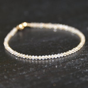 K&ouml;nnte beinhalten: Ein zartes Armband aus kleinen, klaren Perlen mit einem goldenen Verschluss.