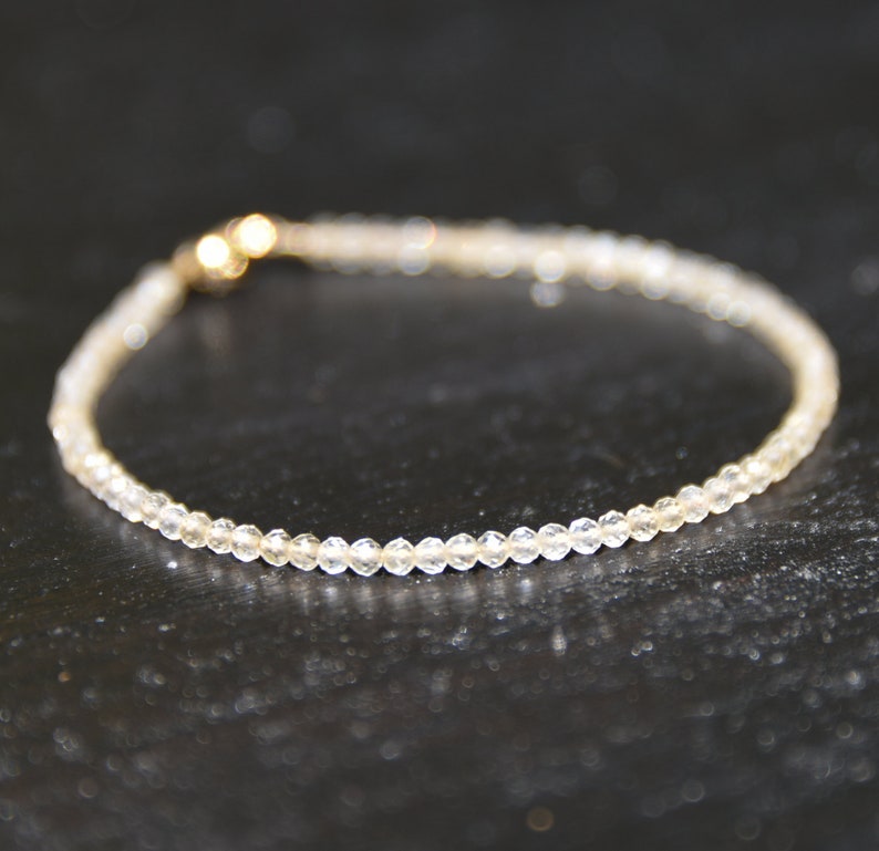 K&ouml;nnte beinhalten: Ein zartes Armband aus kleinen, klaren Perlen mit einem goldenen Verschluss.
