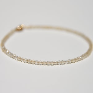 K&ouml;nnte beinhalten: Ein zartes Armband aus kleinen, klaren, facettierten Perlen. Das Armband ist d&uuml;nn und hat ein schlichtes, elegantes Design.