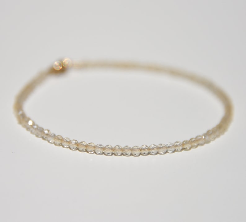 K&ouml;nnte beinhalten: Ein zartes Armband aus kleinen, klaren, facettierten Perlen. Das Armband ist d&uuml;nn und hat ein schlichtes, elegantes Design.