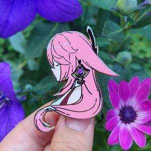 May include: Pink and gold enamel pin featuring a cartoon character with long pink hair, a purple gem, and a white and gold design. The character is looking down and has a soft expression.