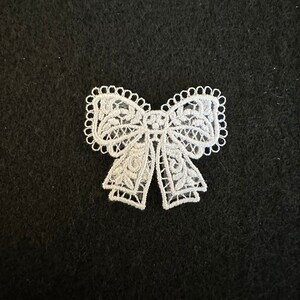 Puede incluir: Lazo de encaje blanco con un delicado diseño floral. El lazo es perfecto para agregar un toque de elegancia a cualquier proyecto.