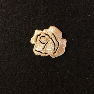 May include: A gold embroidered rose patch. The rose is a single bloom with a detailed design.