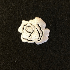 以下が含まれることがあります： 黒い背景に白いバラの刺繍ワッペン。 バラは繊細なステッチで詳細に描かれ、花びらと中心部が際立っています。 生地装飾やクラフトプロジェクトに適しています。