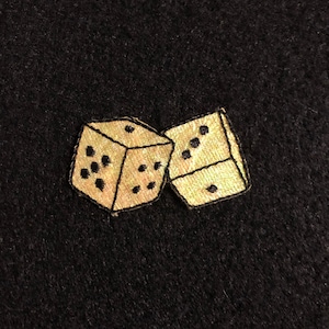 May include: Two gold dice with black dots, embroidered on a black fabric background.