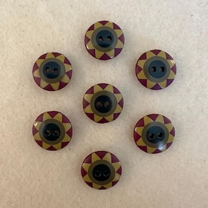 May include: Eight brown buttons with a gold and black sun design. The buttons have two holes.