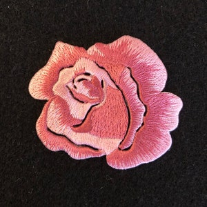 May include: A pink embroidered rose patch. The rose is a single bloom with a detailed design.