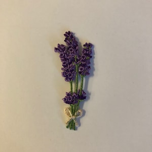 May include: A purple lavender flower embroidery with green stems and a white bow.