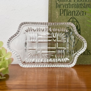 Könnte beinhalten: Eine klare Glasschale mit einem dekorativen, geometrischen Muster. Die Schale hat einen gewellten Rand und ist perfekt zum Servieren kleiner Snacks oder Vorspeisen.