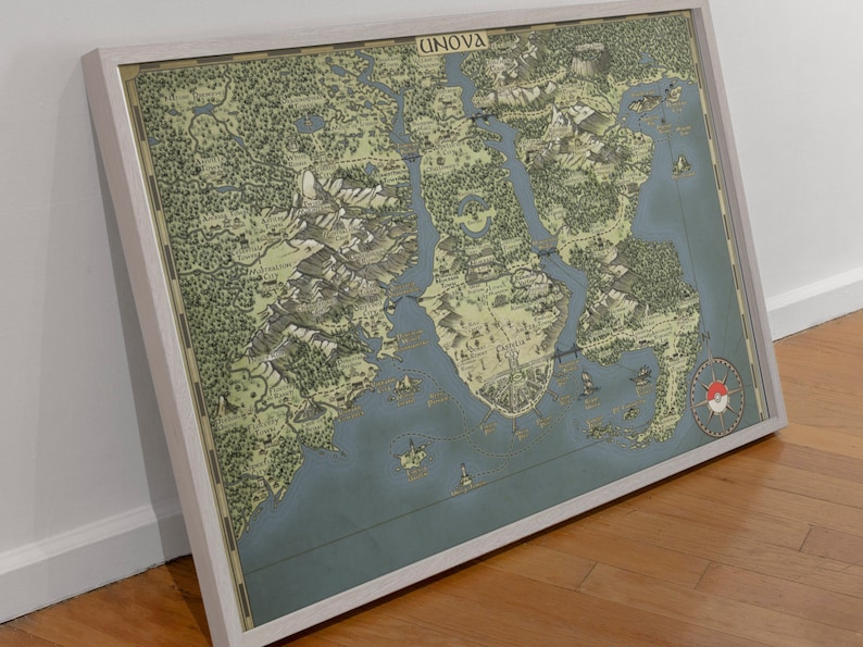 May include: A framed map of the Unova region from the Pokemon video game series. The map is in a vintage style with a blue and green color scheme. The map shows the different cities, towns, and routes in the region. The map is framed in a white frame.
