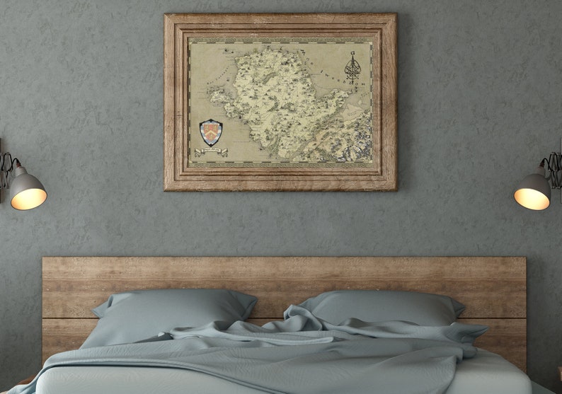 May include: A framed map of a fictional island with a coat of arms in the bottom left corner. The map is in a rustic wooden frame and is hanging on a gray wall above a bed with a wooden headboard and blue bedding.