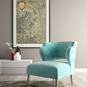 May include: A teal blue armchair with a high back and a cut-out design in the back. The chair is sitting on a patterned rug in front of a white wall and a framed map with the text "North Sea" on it.