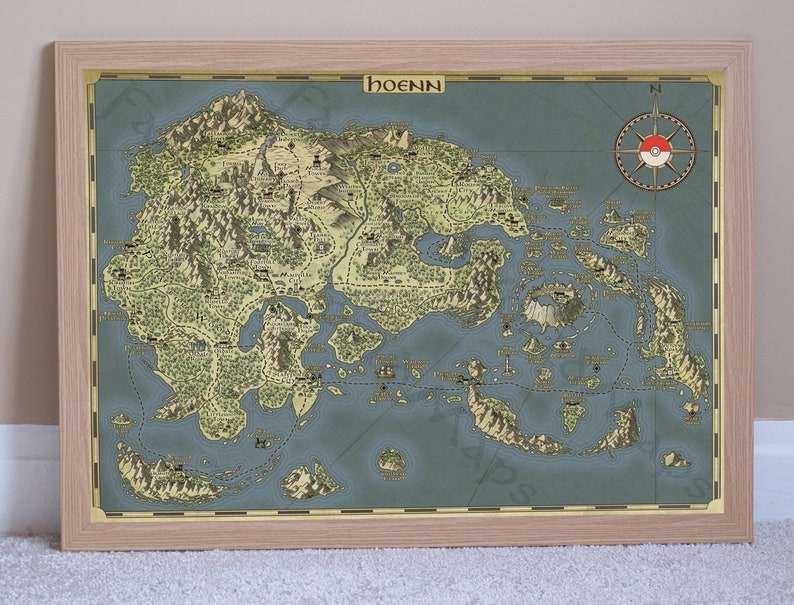 May include: A vintage-style map of the Hoenn region from the Pokemon video game series. The map is printed on a blue background with brown and green landmasses. The map is framed in a light wood frame.