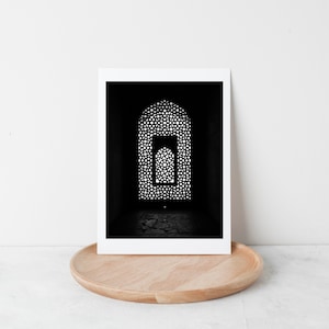 May include: Black and white photograph of a stone archway with intricate latticework. The archway is lit from behind, creating a silhouette effect.
