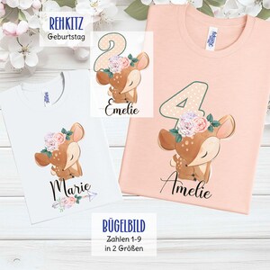 Könnte beinhalten: Weiße und pfirsichfarbene T-Shirts mit einem Hirsch-Motiv, das einen Blumenkranz trägt. Die Shirts tragen die Namen "Marie" und "Amelie" sowie die Zahlen "2" und "4". Der Text "REHKITZ Geburtstag" und "BÜGELBILD Zahlen 1-9 in 2 Größen" sind ebenfalls sichtbar.