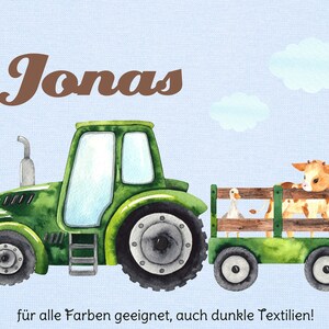 May include: Watercolor illustration of a green tractor pulling a wagon with a cow and a goose. The name "Jonas" is written in brown script above the tractor. Light blue background with white clouds.