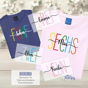 Könnte beinhalten: Zwei T-Shirts, eines in Marineblau und eines in Hellrosa, mit farbenfrohen Textdesigns. Das marineblaue Shirt trägt die Aufschrift "FUNF Lukas" und das rosa Shirt "SECHS Mia". Mehrere Namensaufkleber sind ebenfalls sichtbar. Das Bild enthält auch den Text "BÜGELBILD".
