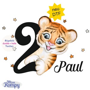 Könnte beinhalten: Aquarell-Illustration eines Tigerbabys mit orangefarbenen und braunen Streifen, neben einer großen schwarzen Zahl 2. Der Name "Paul" ist in Schreibschrift geschrieben. Das Bild enthält Sterne und deutschen Text.