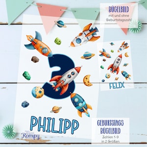 Könnte beinhalten: Ein weißes Bügelbild mit Weltraum-Motiven, darunter Raketen, Planeten und die Zahl 3. Der Name "PHILIPP" ist blau gedruckt, zusammen mit dem Text "FELIX". Zusätzlicher Text enthält "BÜGELBILD" und "GEBURTSTAGS BÜGELBILD".
