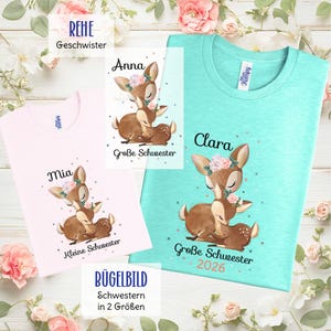 Könnte beinhalten: Rosa und türkisfarbene T-Shirts mit Hirschgrafiken und Text. Das rosa Shirt sagt "Mia" und "Kleine Schwester". Das türkisfarbene Shirt sagt "Clara" und "Große Schwester 2026". Eine Karte sagt "Anna" und "Große Schwester".