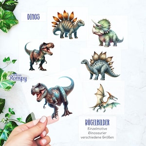 Peut inclure: Plusieurs illustrations de dinosaures sur des cartes blanches. Les cartes présentent divers dinosaures dans des tons de vert, de marron et de bleu. Le texte sur les cartes comprend "DINOS" et "Miss Rompy".