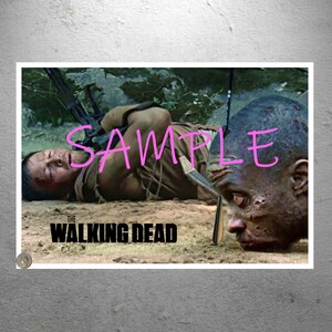 Puede incluir: Un póster de "The Walking Dead" que representa una escena dramática con un hombre en el suelo y una cabeza de zombi. La palabra "SAMPLE" está escrita en rosa en la imagen. El título de la serie se muestra en la parte inferior.