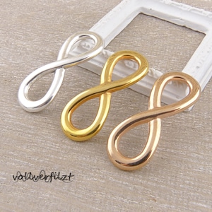 Könnte beinhalten: Drei Unendlichkeits-Anhänger in Silber, Gold und Roségold.