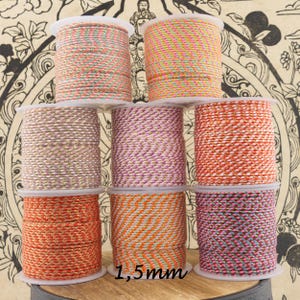 Könnte beinhalten: Eine Sammlung bunter Spulen mit dekorativem Kordel. Die Kordeln sind in verschiedenen Farben, darunter Rosa, Orange und Gold, mit metallischem Glanz. Der Text "1,5mm" ist sichtbar. Die Kordeln werden wahrscheinlich zum Basteln oder zur Schmuckherstellung verwendet.
