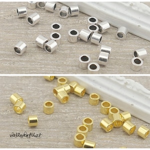 Könnte beinhalten: Eine Sammlung von silbernen und goldenen Sprungringen. Die Sprungringe sind klein und rund, mit einem Loch in der Mitte. Sie sind perfekt für die Schmuckherstellung und andere Handarbeiten.