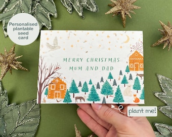 May include: A personalized plantable seed card with a winter scene illustration. The card features a small house, trees, and animals. The text on the card reads "Merry Christmas Mum and Dad".