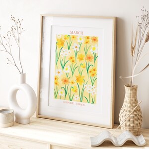 May include: A framed print with a yellow background featuring a pattern of yellow and white daffodils and jonquils. The text "MARCH" is at the top of the print and "DAFFODIL JONQUIL" is at the bottom.