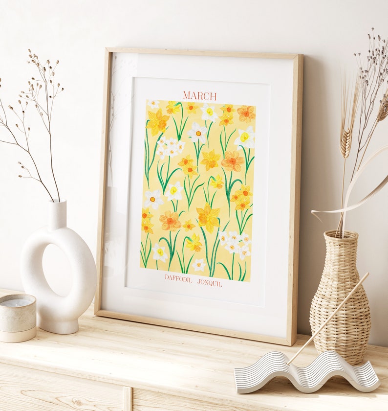 May include: A framed print with a yellow background featuring a pattern of yellow and white daffodils and jonquils. The text "MARCH" is at the top of the print and "DAFFODIL JONQUIL" is at the bottom.