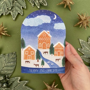 Merry and Bright snowglobe card. 3 decorated gingerbread houses in the snow. Swans in the river. Reindeers and fir trees in the on land. Clouds with snow, moon and stars above.