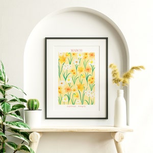 May include: A framed print with a yellow background and a pattern of yellow, white, and orange daffodils. The text "MARCH" is at the top of the print and "DAFFODIL, JONQUIL" is at the bottom.