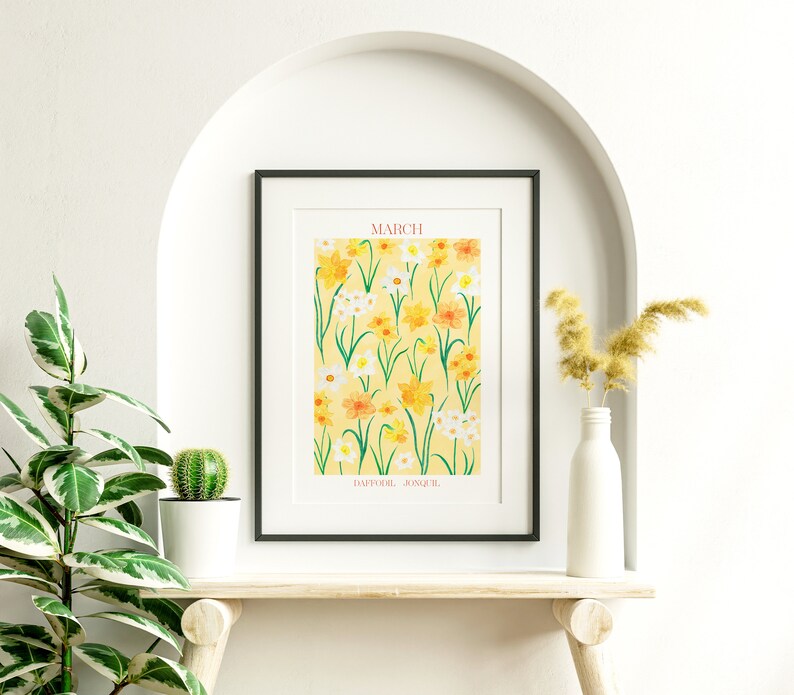 May include: A framed print with a yellow background and a pattern of yellow, white, and orange daffodils. The text "MARCH" is at the top of the print and "DAFFODIL, JONQUIL" is at the bottom.