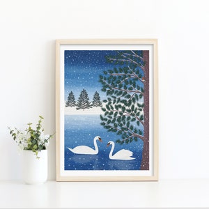 Christmas art print with mock up oak frame with 2 swans in a lake, a tree in the foreground with a robin perched on a branch and 3 christmas trees in the background. The daytime blue sky background and falling snow.