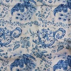 Può includere: Tessuto bianco con un motivo blu ripetuto con draghi stilizzati, pavoni ed elementi floreali. Il design ricorda i tradizionali motivi Chinoiserie, creando un'estetica classica ed elegante.