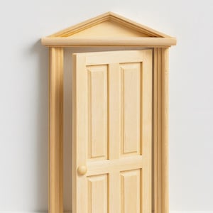 Könnte beinhalten: Eine Miniatur-Holztür, die sich in ihrem Rahmen öffnet. Die Tür hat eine helle Holzoberfläche mit vier rechteckigen Paneelen und einem runden Türknauf. Der Rahmen hat einen dreieckigen Giebel an der Oberseite.