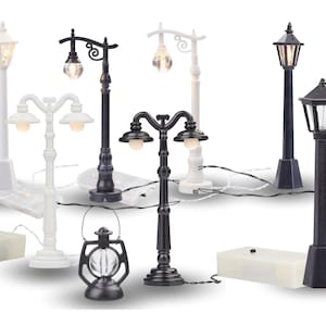 Könnte beinhalten: Set aus schwarzen und weißen Miniatur-Straßenlaternen mit LED-Lichtern. Die Lichter sind an einem weißen Kabel und haben einen Akkupack.