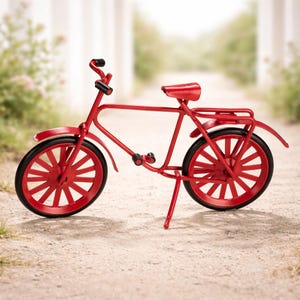 Könnte beinhalten: Ein Miniatur-Fahrradmodell aus Metall in leuchtendem Rot. Das Fahrrad verfügt über dünne rote Speichen, schwarze Reifen, einen roten Sattel, einen Gepäckträger und schwarze Lenkergriffe. Es wird von einem einzelnen Ständer auf einer hellen Fläche gehalten.