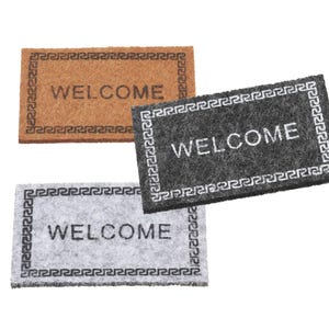 Könnte beinhalten: Drei Willkommensmatten mit einem dekorativen Rand. Die obere Matte ist braun mit dem Wort "WELCOME" in Schwarz. Die mittlere Matte ist grau mit dem Wort "WELCOME" in Weiß. Die untere Matte ist weiß mit dem Wort "WELCOME" in Schwarz.