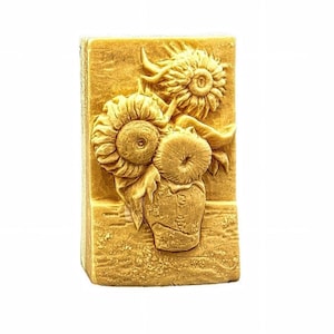 May include: A rectangular bar of soap with a raised design of sunflowers in a vase. The soap is a light brown color.
