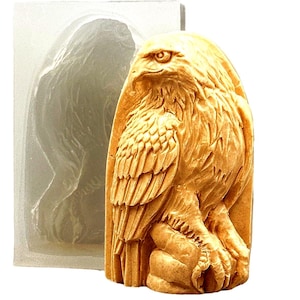 May include: A detailed, realistic eagle sculpture made of a light brown material. The eagle is perched on a branch with its wings spread out. The sculpture is in a clear silicone mould.