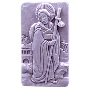 Könnte beinhalten: Eine violette rechteckige Plakette mit einem Reliefbild eines Mannes in einer Robe, der einen Stab hält. Der Mann trägt einen Heiligenschein und steht vor einem Gebäude mit Palmen.