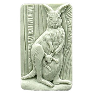 May include: A green soap bar with a detailed carving of a kangaroo carrying a joey in its pouch. The soap is set against a background of carved leaves.