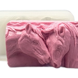 K&ouml;nnte beinhalten: Eine rosa Silikonform zum Herstellen von Seife oder Kunstharz. Die Form zeigt zwei Pferdek&ouml;pfe, die sich gegen&uuml;berstehen und sich mit der Nase ber&uuml;hren.